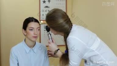 有经验的验光师在眼科门诊用检眼镜检查漂亮的女病人;有光学设备的眼科医生用检眼镜检查病人的视力